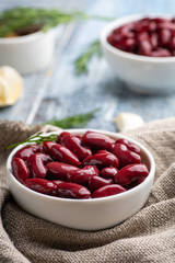 Red kidney beans from can in white bowl on a table.