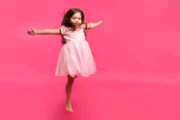 Cute little girl dreams of becoming a ballerina. Little Dancing Girl. Studio Shoot Over Pink Background