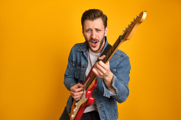 A portrait of funny handsome musician playing electric guitar, singing a song