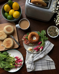 Homemade breakfast with toasted bagels, ham, radishes, coffee, seeds, limes and lemons