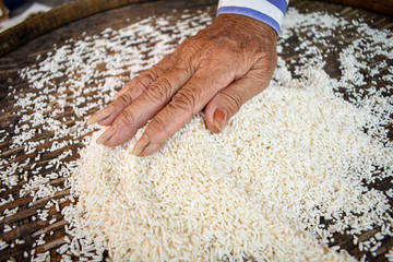 White rice on a wooden background and farmers are drying rice outdoors. 