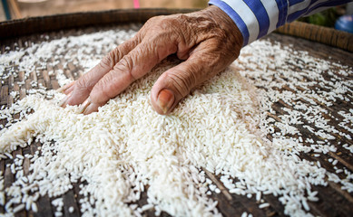 White rice on a wooden background and farmers are drying rice outdoors. 