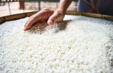 White rice on a wooden background and farmers are drying rice outdoors. 