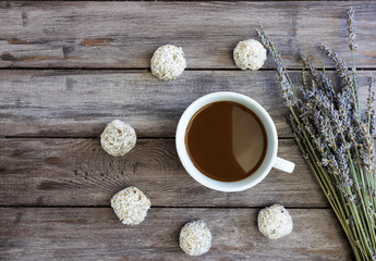 Cup of coffee with protein balls or energy balls on a wooden background, against the background of lavender flowers, a healthy breakfast of raisins, oatmeal, nuts, chia seeds in coconut © Iryna