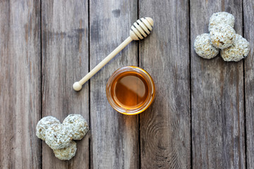 Homemade diet candy of dates and apricot in coconut filling on a wooden background with a jar of honey, flat lay, copy space