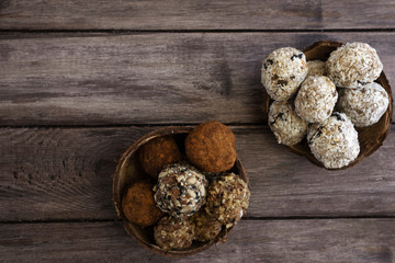 Homemade truffles, protein bars or energy bars with dried apricot bananas and oatmeal honey in a coconut scarlet on a wooden background, top view