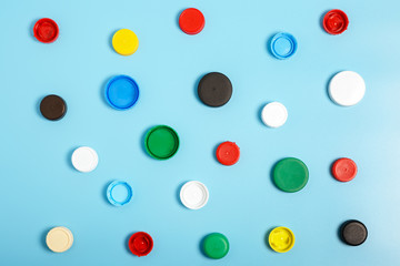 Multi-colored plastic bottle caps on a blue background. The problem of environmental pollution. Top view, Pattern. Recycling plastic.