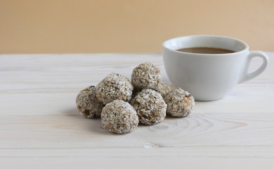 A healthy breakfast, protein balls or energy balls in a heap next to a white cup of coffee on a light background, good Monday, a snack at work