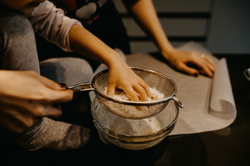 Little girl mixing flour with eggs, making dough. Mother and little daughter baking cookies at home.