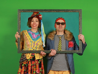 Funny freaky couple posing in the studio holding a picture frame in their hands