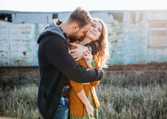 Young couple of man and woman outdoors, man hugging woman from behind.