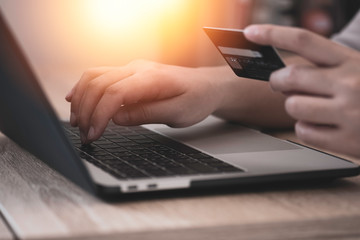 Woman hand holding credit card and  input order to computer laptop. Online shopping during work from home and new normal concept.
