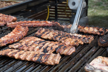 Chef cooking fresh pork ribs on the charcoal grill, during food festival, street food