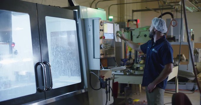 Man operating CNC mill in workshop
