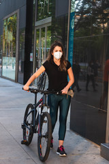 Chica joven de ojos claros, yendo en bicicleta durante coronavirus en una ciudad.