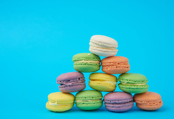 stack of multi-colored round baked macarons cakes on a blue background