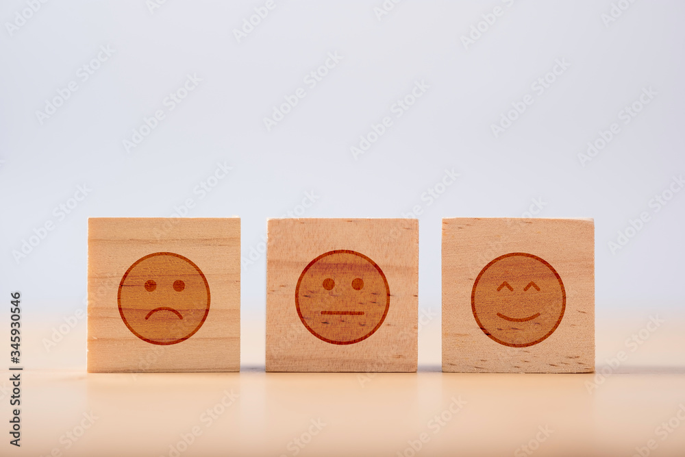 Poster smiley emotion to among normal and sad emotion which print screen on wooden cubic. customer experien