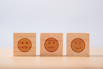 smiley emotion to among normal and sad emotion which print screen on wooden cubic. Customer...