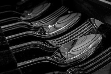 row of stainless steel silverware in a canteen showing forks, and spoons