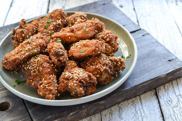 Baked chicken wings with sesame seeds. Ketchup and chili sauce. Free space for text. Wooden background. Delicious fried chicken wings. Close up