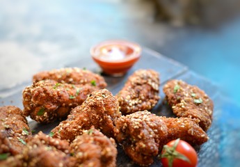 Baked chicken wings with sesame seeds. Ketchup and chili sauce. Free space for text. Wooden background. Delicious fried chicken wings. Close up