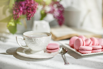 A Cup of morning coffee, a bowl of lilac, macaroni, on a light background. Postcard good morning
