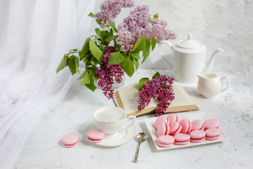 A Cup of morning coffee, a bowl of lilac, macaroni, on a light background. Postcard good morning