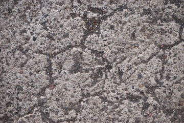 Closeup detail of rough stone surface texture with gritty sand grains in irregular grooves and scratches