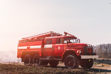 red firetruck on field with faded grass against sky. Concept of