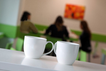 coffee time / two cups in the foreground and three girls in the background