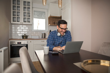 Portrait of businessman wearing headphones working remotely on his laptop.