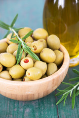 Fresh healthy green olives with rosemary and virgin oil in a bottle on wooden table