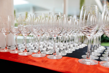 Set up a lot of clear and clean empty wine glasses in row on the table