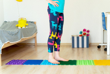 little girl walks bare feet on rubber massage mat at home