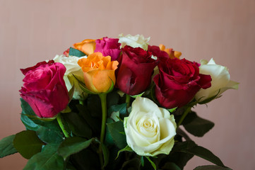 Lovely big colorful bouquet with many flowers  roses of red, vinous, orange and white colors. Green leaves and thorns. Still life. Calm pink background