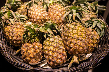 Pile of fresh pineapples in wooden wicker basket for sales in a local market or supermarket