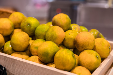 Pile of fresh Tangerine or Thai oranges in wooden crate box for sales in a local market or supermarket