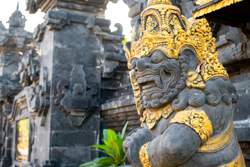 Fototapeta na wymiar Balinese stone statue against the blue sky and trees