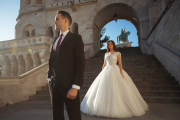 Bride and groom hugging in the old town street. Wedding couple walking on the Fisherman's Bastion, Budapest, Hungary. Happy romantic young couple celebrating their marriage. Wedding and love concept.
