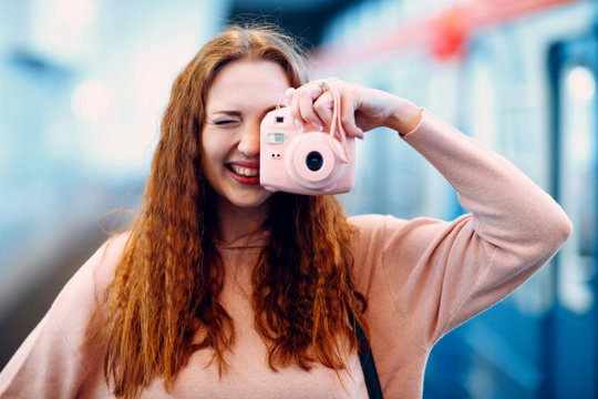 Young girl takes pictures on a pink camera and laughs