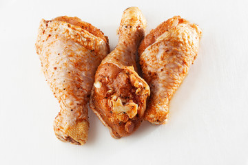 Raw drumsticks on white background. Chicken legs. Raw chicken marinated legs. Top view. Food Background. Cooking content. Uncooked meat. Meat shop concept.