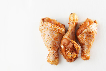 Raw drumsticks on white background. Chicken legs. Raw chicken marinated legs. Top view. Food Background. Cooking content. Uncooked meat. Meat shop concept.