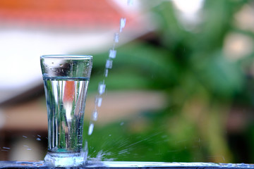 pouring purified fresh drink water from the bottle on wood counter and space for text