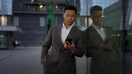 Front view of a young asian businessman, leading correspondence on the phone. Financial business area.