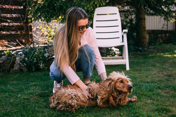 Young smiling woman playing with her golden dog in the yard.