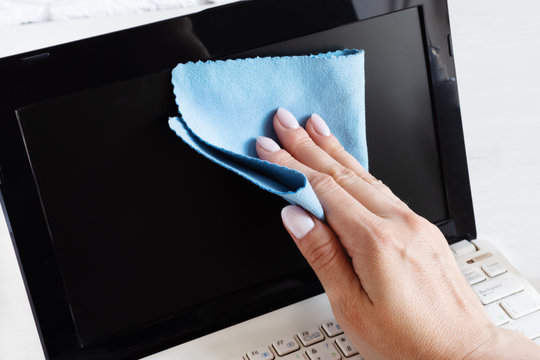 Woman hand disinfecting computer screen with antibacterial cloth.