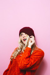 Portrait of smiling blonde girl in winter hat over pink background.	
