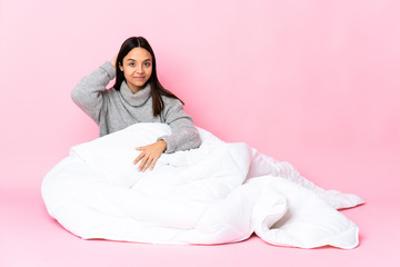 Young mixed race woman wearing pijama sitting on the floor in back position and thinking