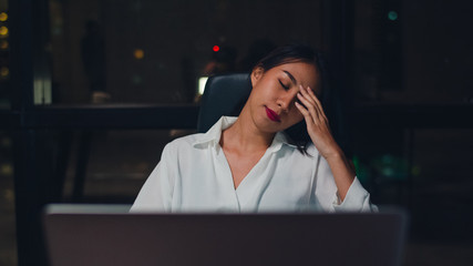 Millennial young Chinese businesswoman working late night stress out with project research problem...