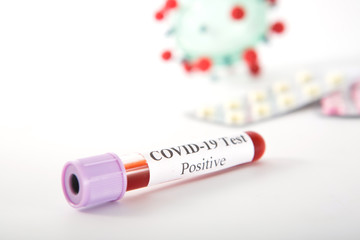 Test tube with a positive COVID-19 test on a white background